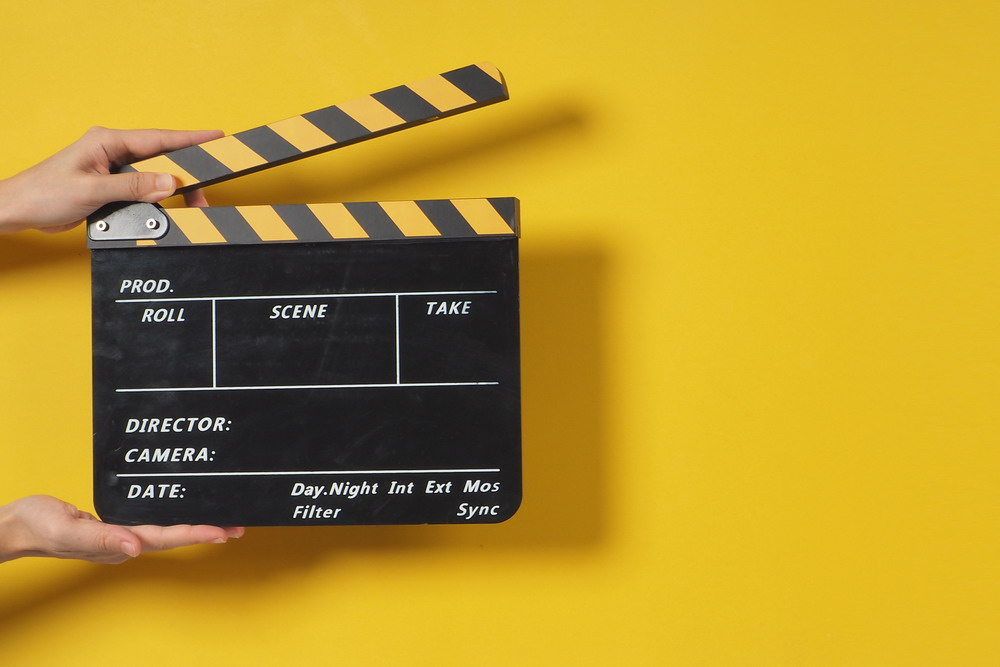 Hand is holding clapper board or movie slate.It is used in video production and film industry on yellow background.