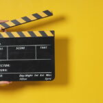 Hand is holding clapper board or movie slate.It is used in video production and film industry on yellow background.
